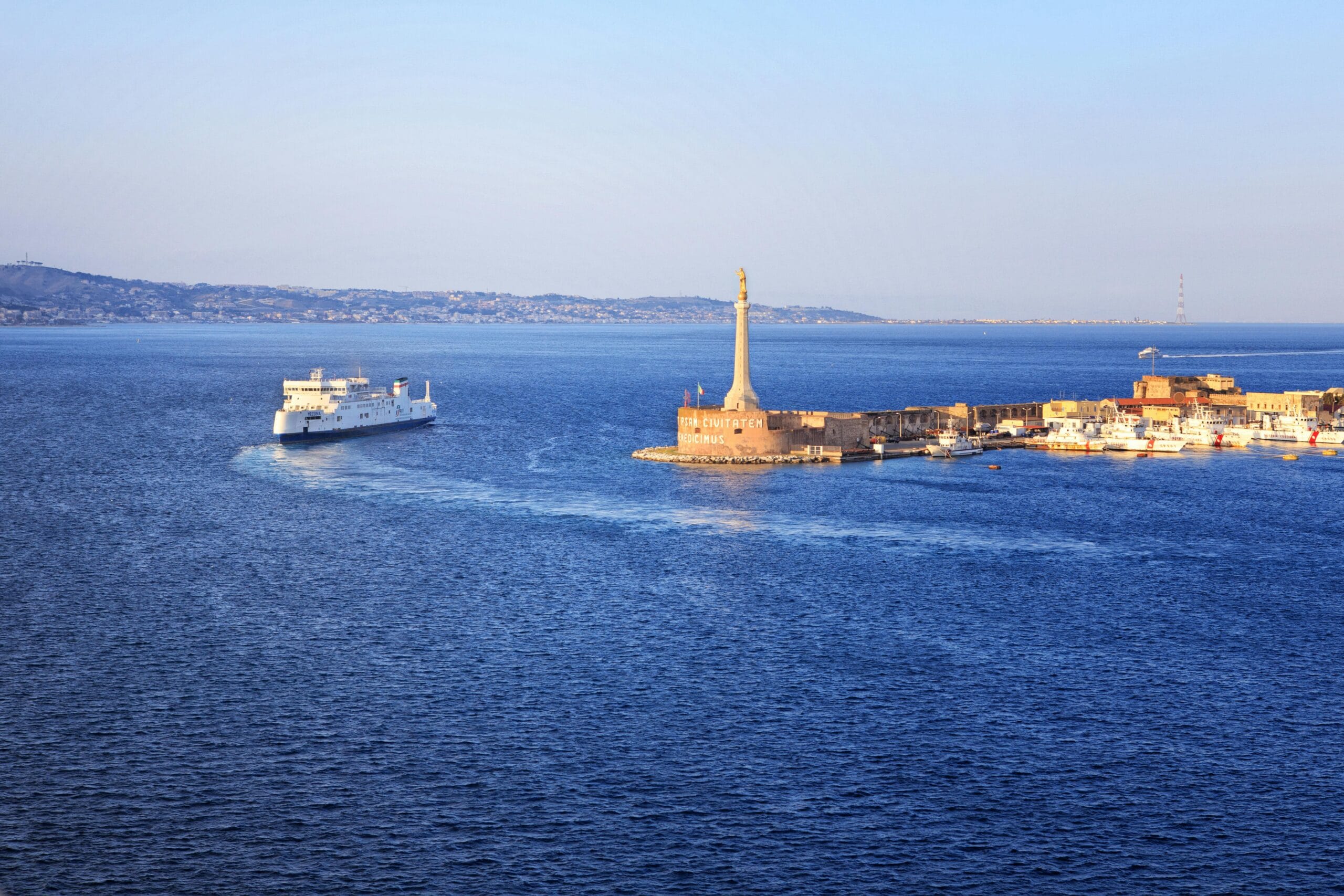 Traghetto in navigazione davanti al porto di Messina con la Madonnina del mare ed il faro